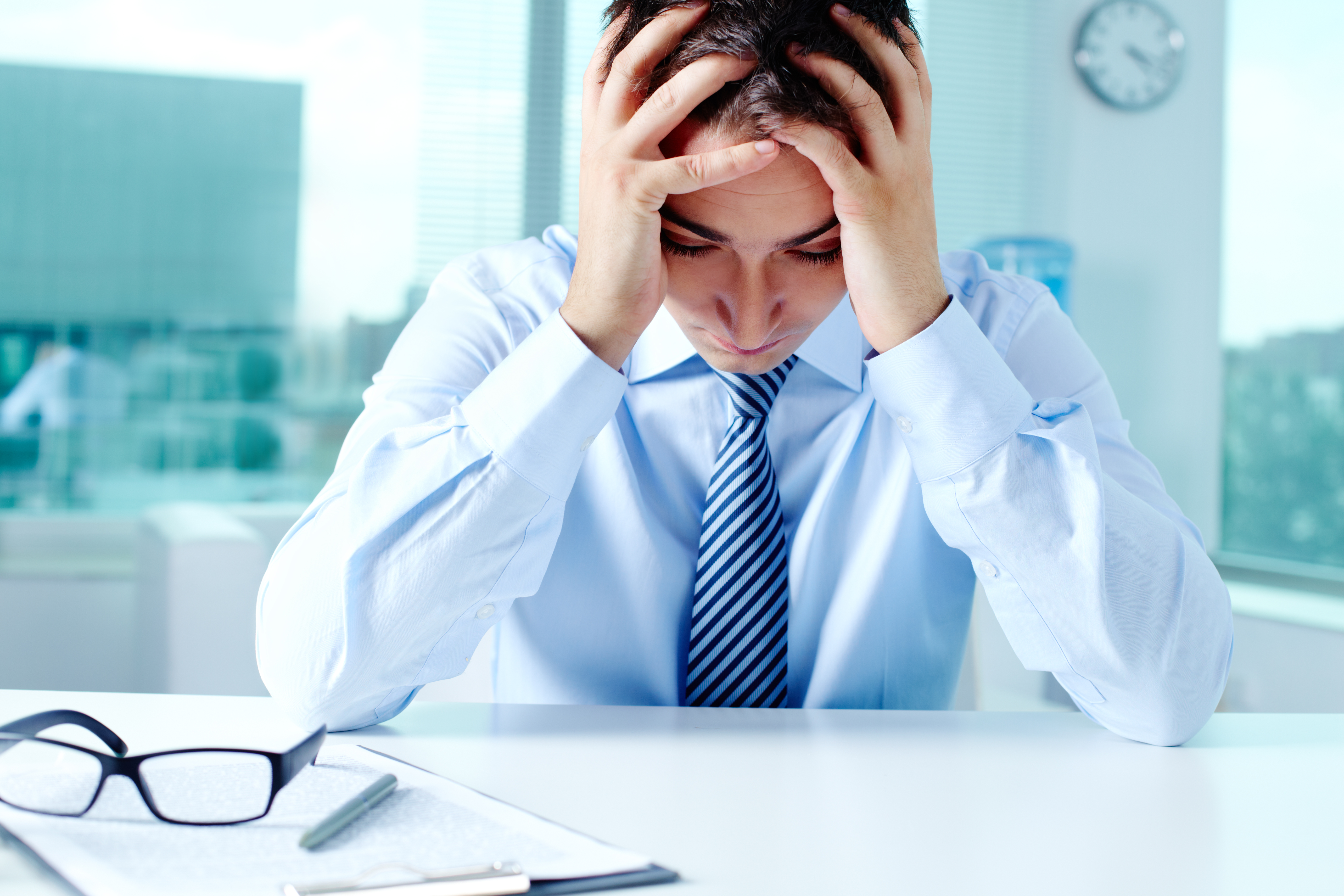 Stressed businessman sitting at workplace and touching his head